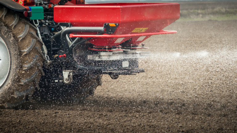 An agricultural machine in action, fertilizing a lawn with synthetic fertilizers for precise and optimal growth