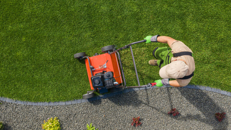 A dedicated worker actively aerating a lawn, demonstrating the process of lawn aeration to alleviate soil compaction and promote a healthy, vibrant landscape