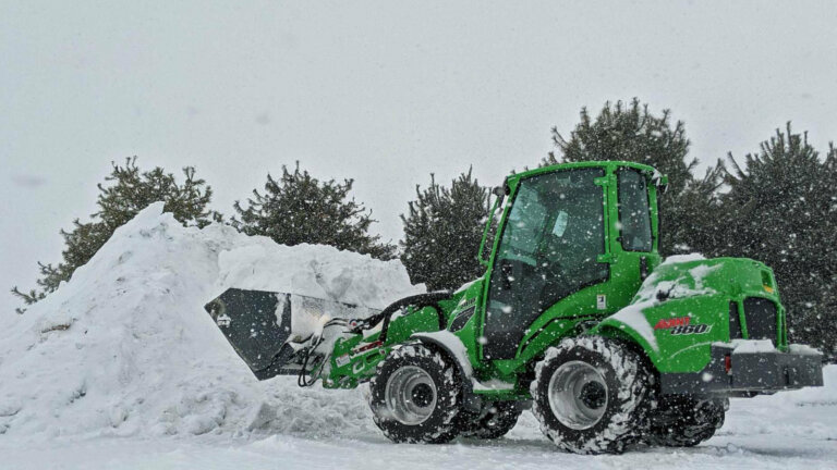 A commercial snow removal machine in action, clearing a large area of snow efficiently, reflecting the importance of choosing a reliable snow removal company for your business