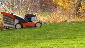 Lawn mower making the final cut of the season on green grass during fall.