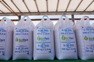 A row of large white bags of fertilizer labeled with their NPK ratios, such as 10-20-6 and 9-30-9, clearly displaying the fertilizer numbers.