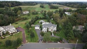 An aerial view of a large home in Montgomery County surrounded by mature trees, a mowed lawn, and open farmland stretching into the distance.